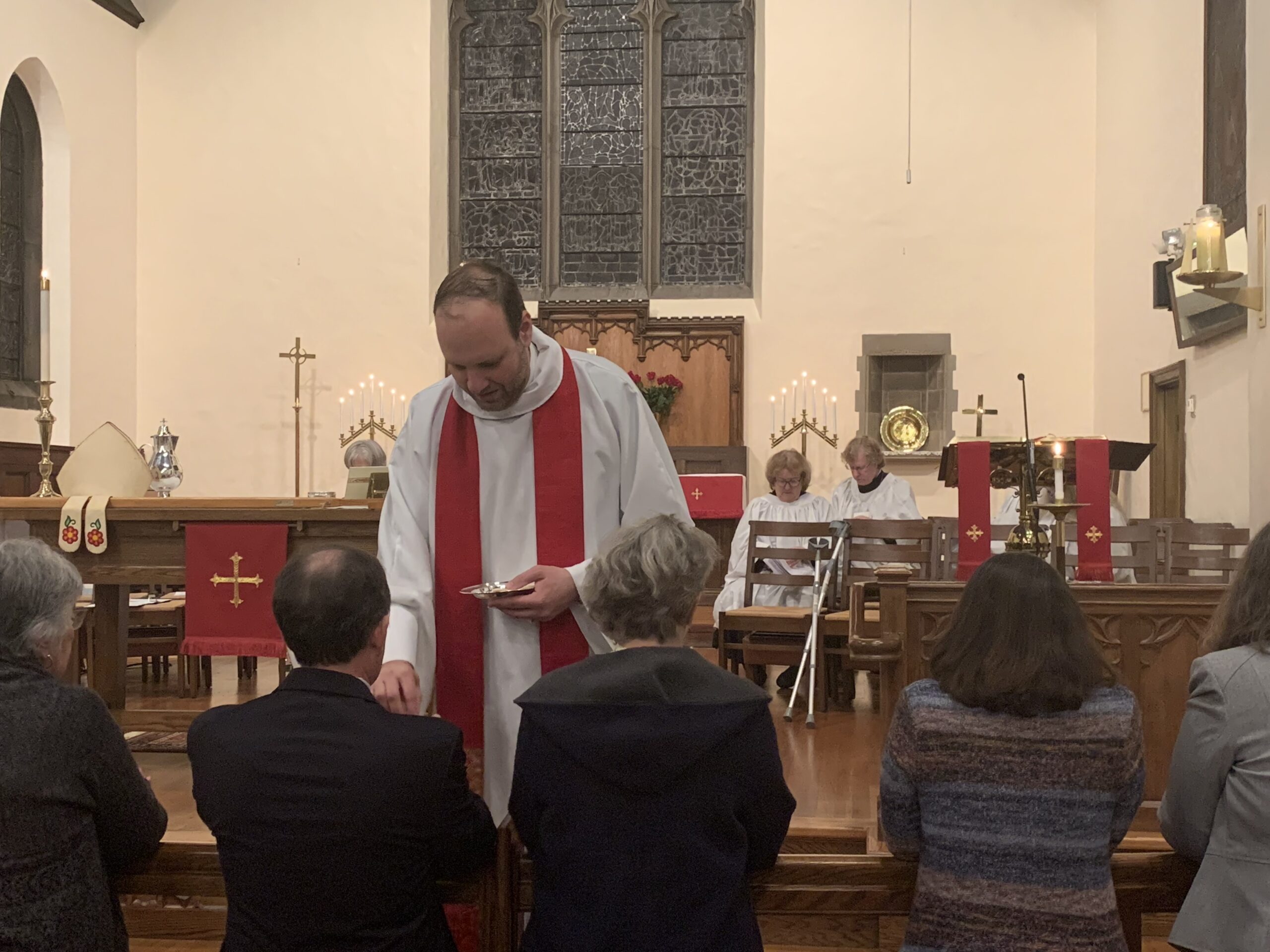 Rev. Whiteman distributes communion to parishioners at the altar rail.
